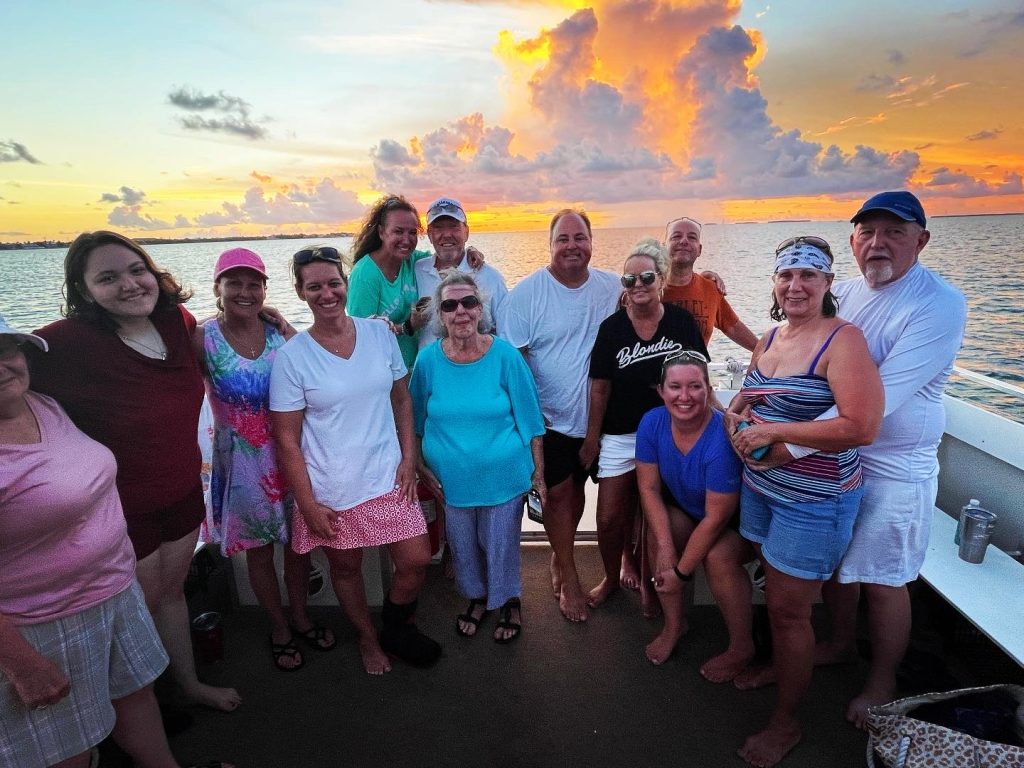 Group of guests smiling on the boat deck at sunset